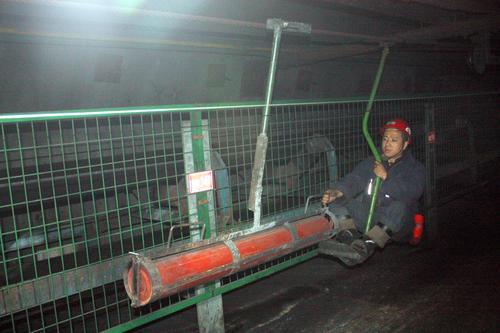 近日，張集煤礦利用廢舊猴車設(shè)計(jì)制作的皮帶托輪運(yùn)輸器，在井下使用后效果明顯。據(jù)該礦職工肖廣華介紹，張集礦膠帶暗斜井全長約兩千多米，由于吊猴乘坐安全規(guī)定，過去皮帶頭的托輪需要更換，全靠人力送到膠帶暗斜井下費(fèi)時(shí)費(fèi)力。現(xiàn)在這種皮帶托輪運(yùn)輸器可以根據(jù)托輪的尺寸進(jìn)行調(diào)節(jié)使用，不僅符合吊猴乘坐安全規(guī)定，而且節(jié)約時(shí)間，降低了職工勞動(dòng)強(qiáng)度。圖為該礦職工正在使用托輪運(yùn)輸器向井下運(yùn)送托輪。